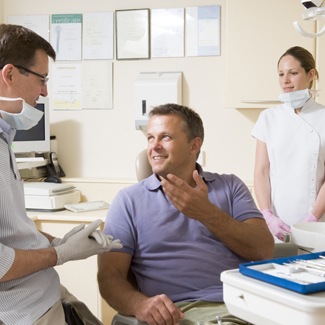 Man talking to dentist in exam room before dental placement