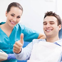 Smiling man in dental chair giving thumbs up