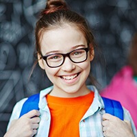 girl with glasses smiling during children's dentistry visit