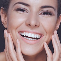 Smiling woman touching face after dental bonding treatment