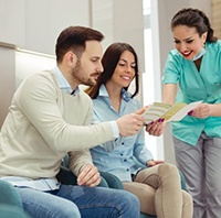 dental team member explaining the cost of emergency dentistry to two patients 