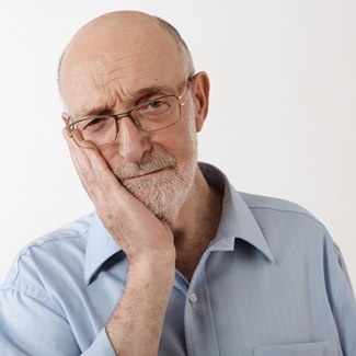 older man holding jaw in pain needs emergency dentistry