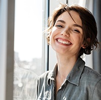 Woman standing next to a window and smiling 