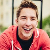 teen boy in red jacket smiling after fluoride treatment