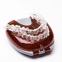A set of Invisalign aligners placed on top of a protective case 