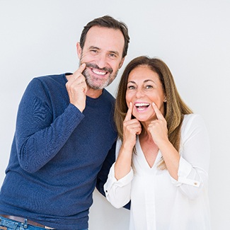 An older couple with dental implants smiling.