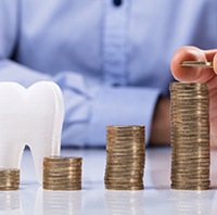 A man stacking coins next to a model tooth.