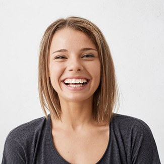 young woman in black shirt with straight teeth thanks to Invisalign
