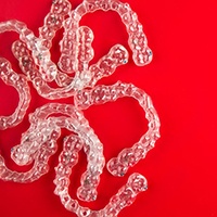 several clear aligners against red background