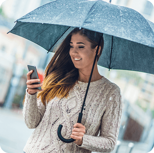 Smiling Woman holding umbrella and looking at her phone