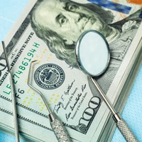 Dental instruments on stack of cash