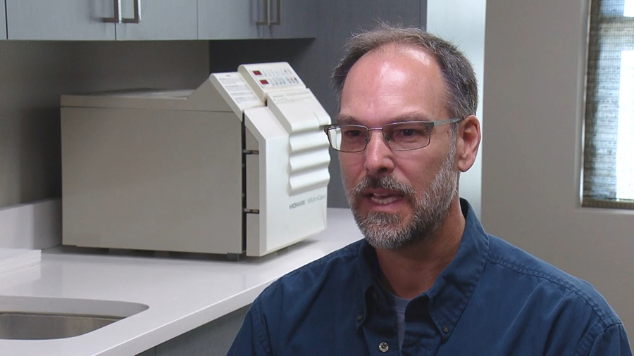 Man in dark blue collared shirt giving interview