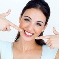Woman pointing to healthy smile after root canal therapy