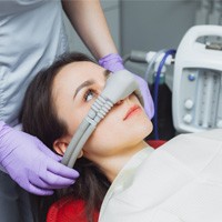 A dentist placing an inhalation sedative mask on a woman