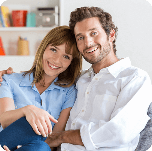 Young man and woman smiling while sitting on living room couch