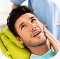 Concerned man cradling in need of TMJ therapy holding jaw