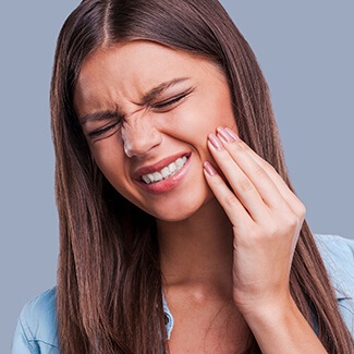 Woman holding jaw in pain needs TMJ therapy