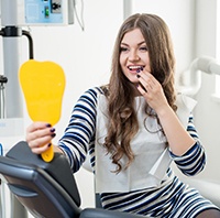 Woman looking at smile in dental mirror