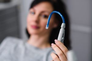 patient holding a dental suction device in their hand