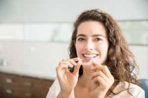 Woman holding Invisalign clear aligner.