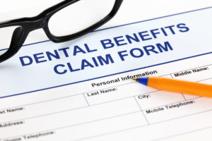Dental benefits claim form with glasses and ballpoint pen
