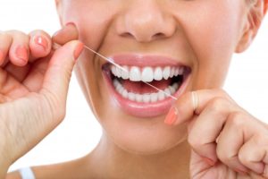 woman smiling using dental floss